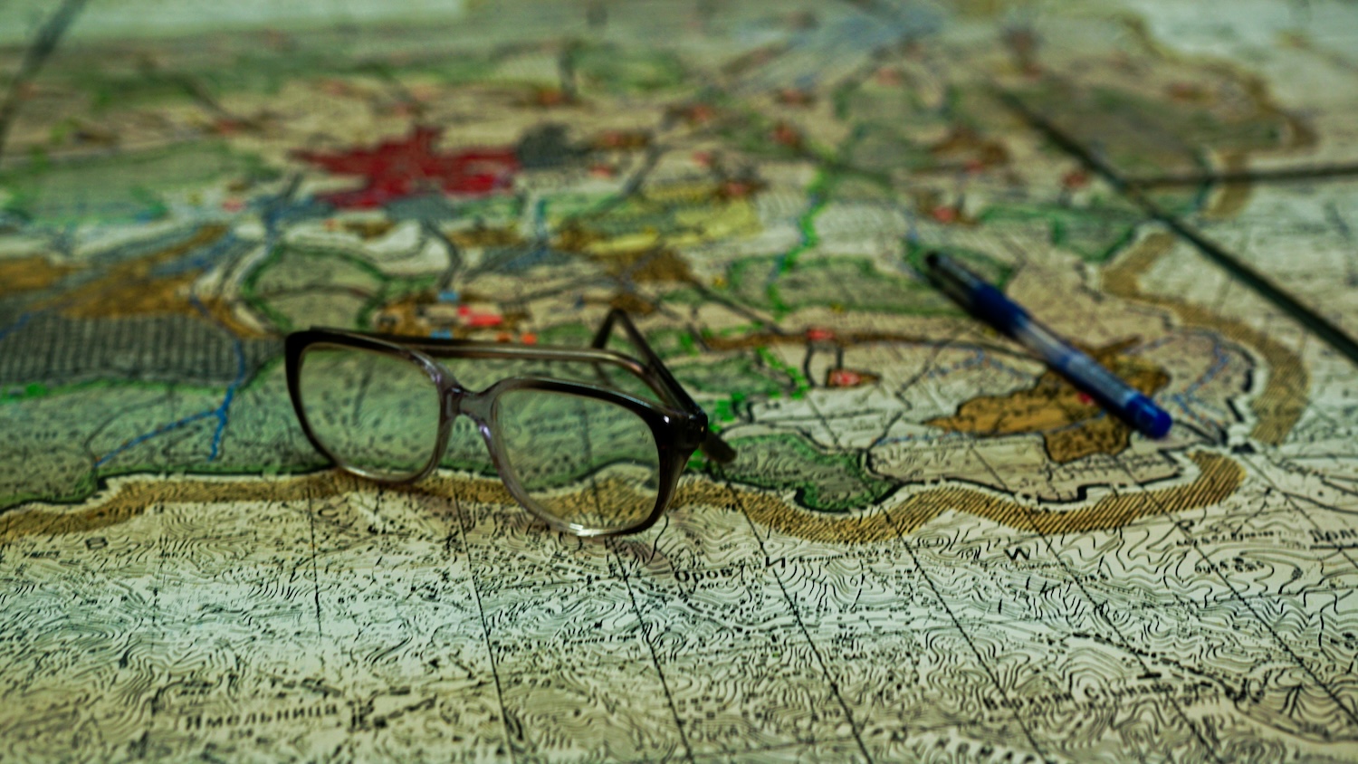a pair of glasses and a pen lying on top of a large map